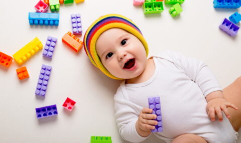 baby-boy-playing-with-multi-colored-constructor-white-wall