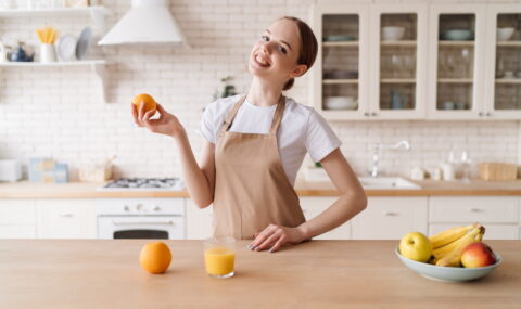 young-beautiful-woman-kitchen-apron-fruits-orange-juice